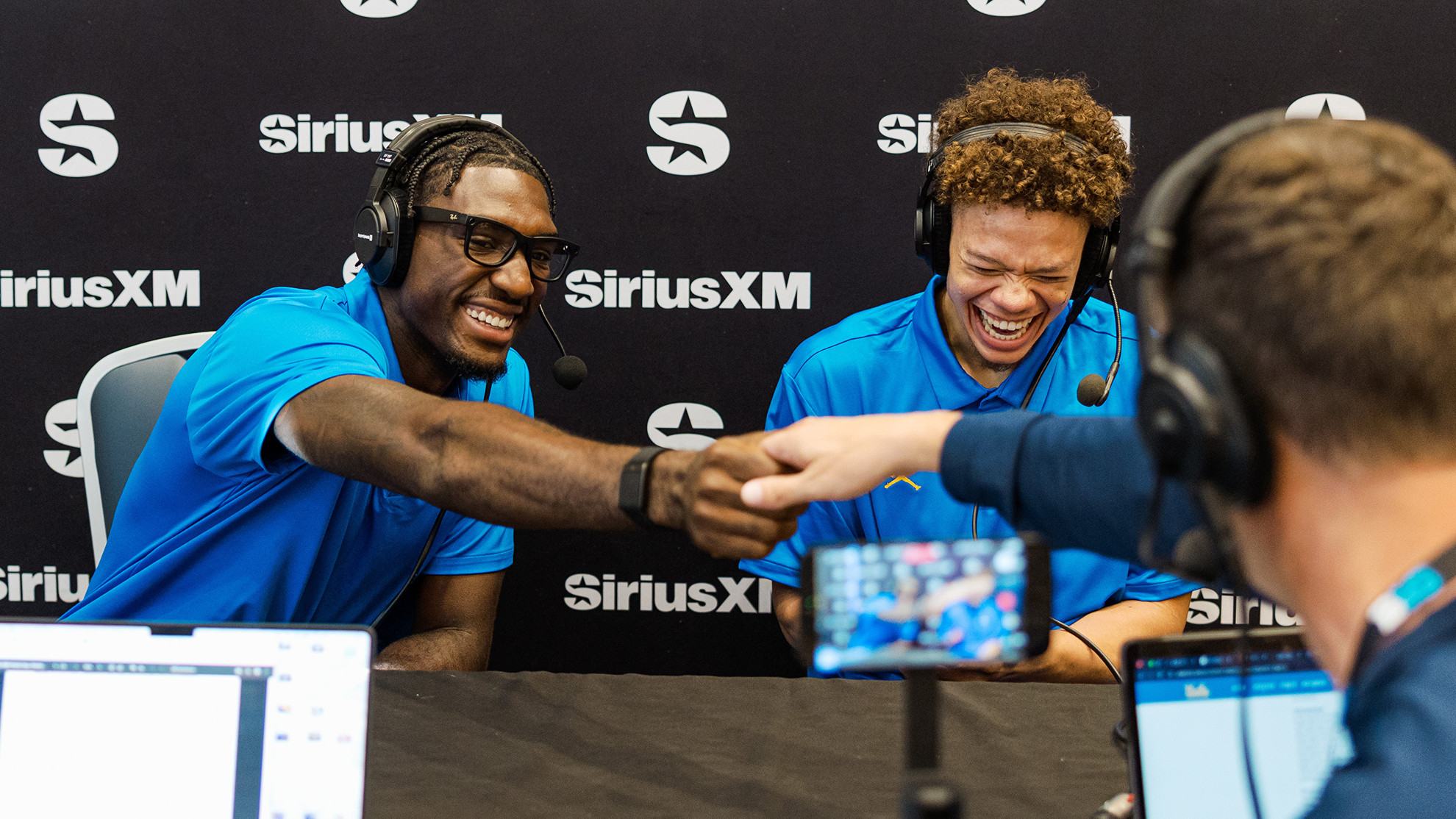Eric Dailey Jr. and Trent Perry laugh as they meet the broadcasters from Sirius XM Radio