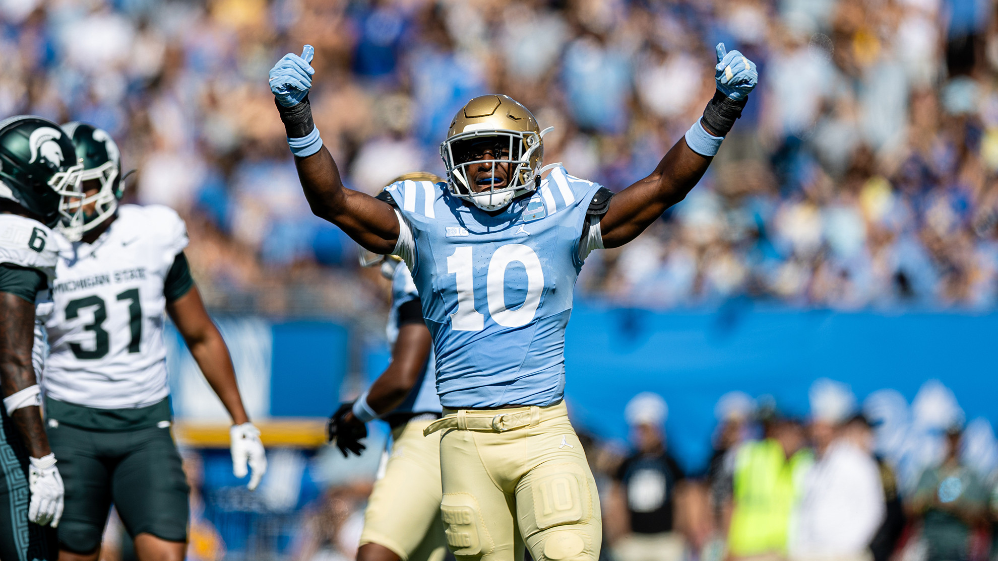 Sammy Omosigho raises his arms to hype up the team after making a big play on defense