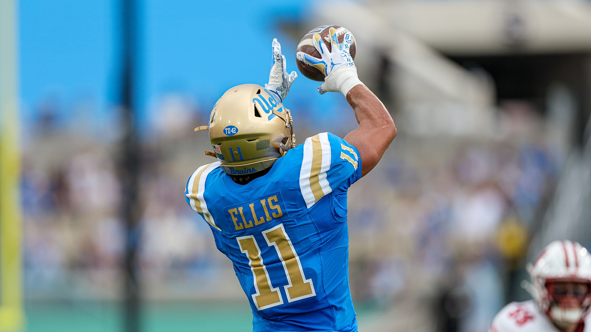 UCLA wide receiver Landon Ellis catches a football during UCLA's 17-7 win over Wisconsin. With both hands outstretched, the back of Ellis' jersey is visible.