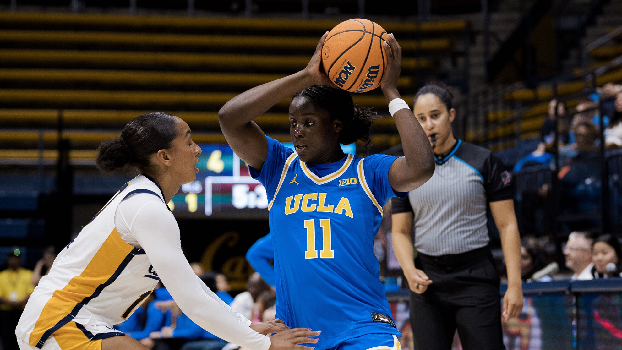 Freshman Somto Okafor holds a basketball over her head to dodge a defender against the California Golden Bears inside Haas Pavilion during UCLA's preseason exhibition game in Berkeley.