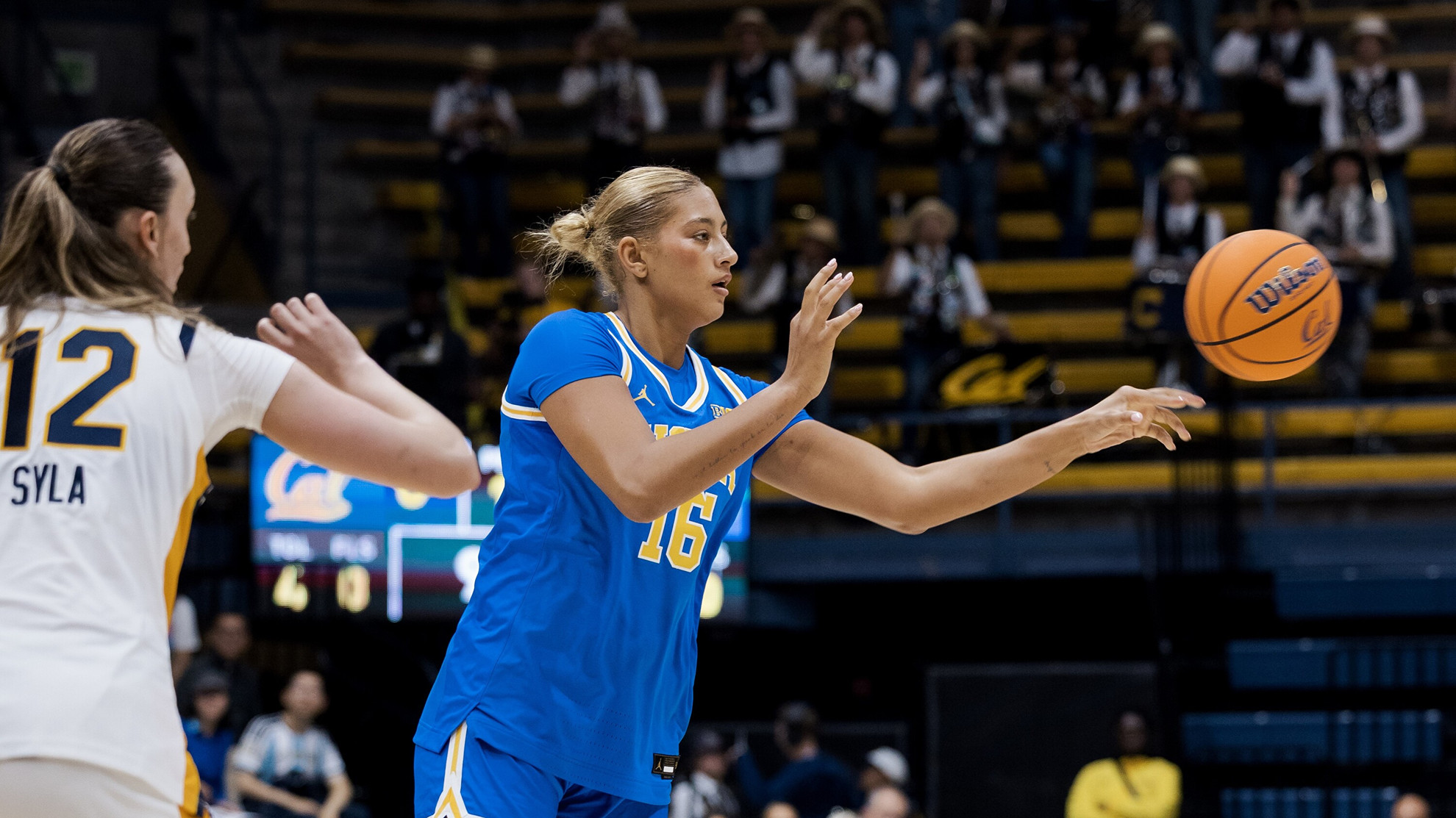 UCLA's Sienna Betts passes a basketball to her teammate (not pictured) during the Bruins' exhibition game at Cal. The basketball has barely left Betts' outstretched left hand.